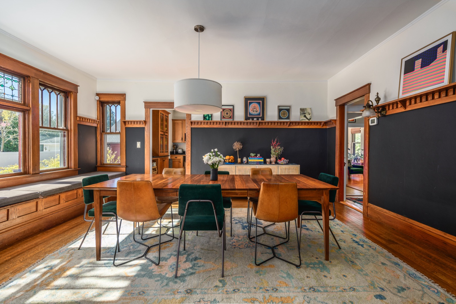 Dining room with deep navy walls, original picture rail, leather and velvet chairs around a long wood table.