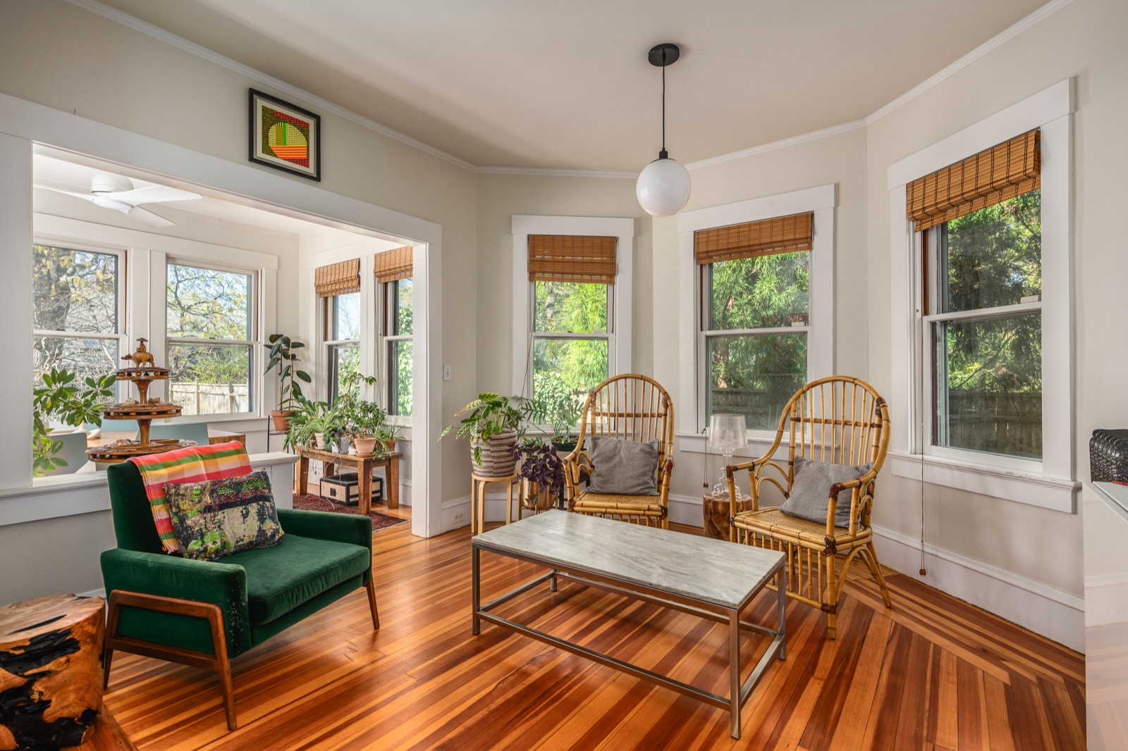 Sunroom with rattan chairs, marble coffee table, and windows on three sides.