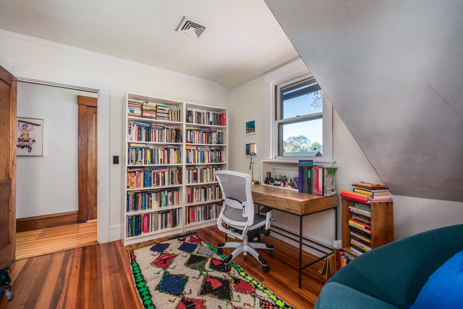 Home office with floor-to-ceiling bookshelves and a desk under the dormer window.