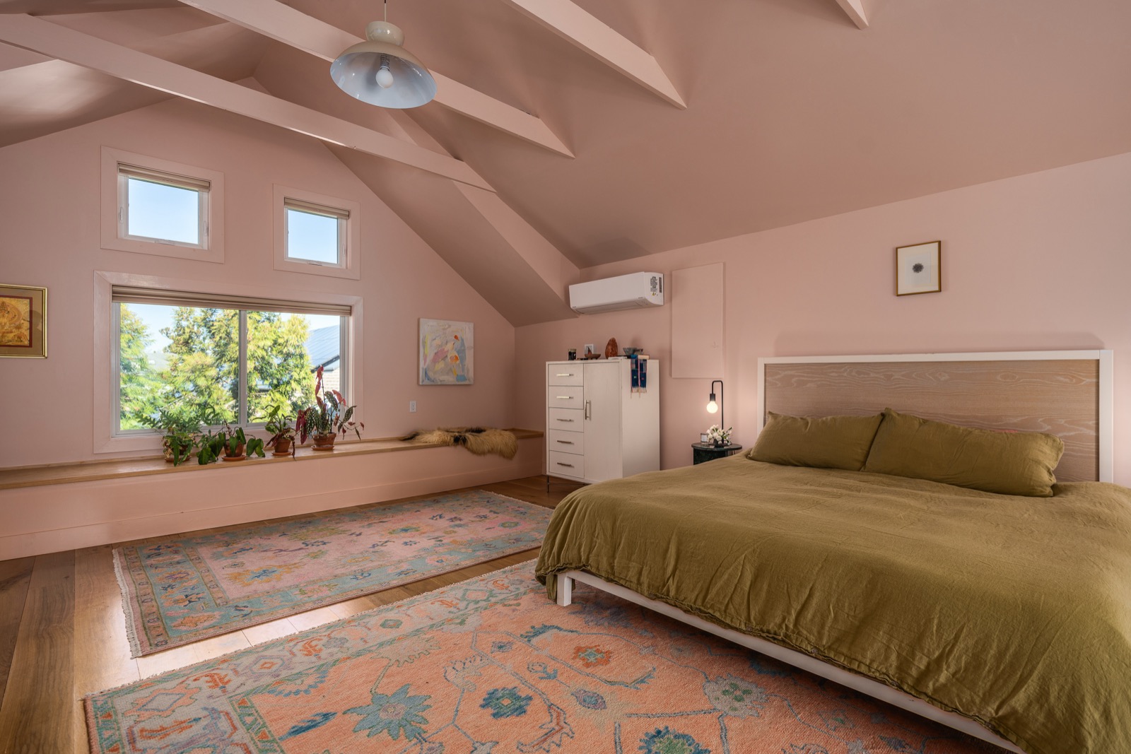 The primary bedroom looking toward a wall of windows with a windowsill of plants.