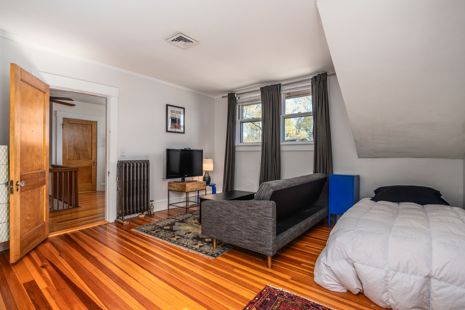 Fourth bedroom with a full bed on the right under the dormer, a full-size futon sofa-bed in the middle, and a TV across from it.